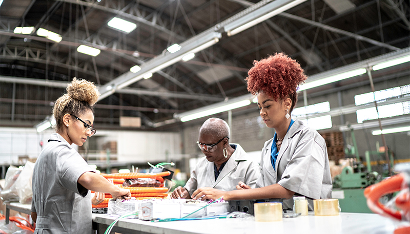 Factory workers in grey robes handling products and material
